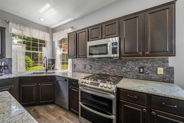 7305 Meadowwood Dr, Rowlett, TX 75089 - kitchen featuring appliances with stainless steel finishes, dark wood finished floors, dark brown cabinets, decorative backsplash, and light stone counters