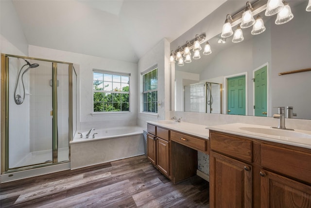 7305 Meadowwood Dr, Rowlett, TX 75089 - bathroom with vaulted ceiling, double vanity, a stall shower, a garden tub, and wood finished floors