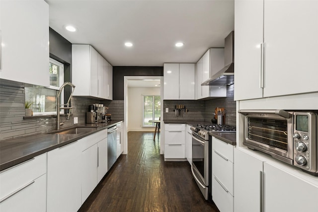 3138 Whirlaway Rd, Dallas, TX 75229 - kitchen featuring stainless steel appliances, wall chimney exhaust hood, dark wood-style flooring, white cabinetry, and dark countertops