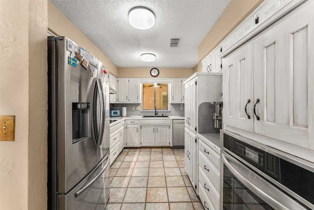 4610 County Road 862, Mckinney, TX 75071 - kitchen with stainless steel appliances, a textured ceiling, light countertops, white cabinetry, and light stone finish flooring