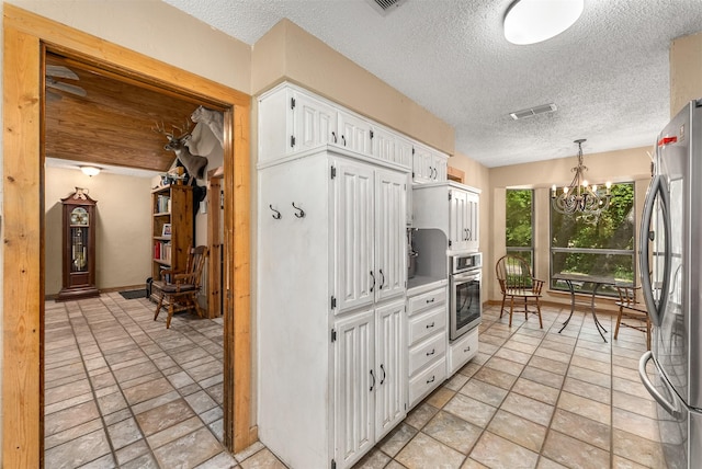 4610 County Road 862, Mckinney, TX 75071 - kitchen with appliances with stainless steel finishes, a chandelier, a textured ceiling, white cabinets, and pendant lighting