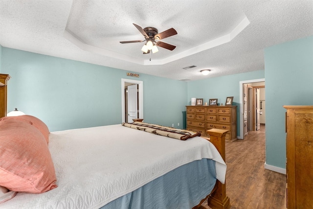 4610 County Road 862, Mckinney, TX 75071 - bedroom featuring a textured ceiling, a tray ceiling, wood finished floors, and a ceiling fan