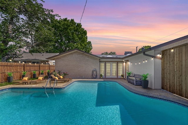 10305 Robindale Dr, Dallas, TX 75238 - pool at dusk with french doors and a patio area