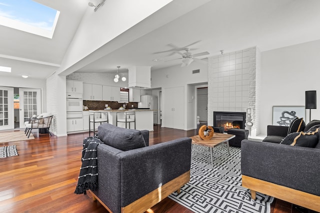 10305 Robindale Dr, Dallas, TX 75238 - living area featuring a fireplace, dark wood-type flooring, a ceiling fan, high vaulted ceiling, and a skylight