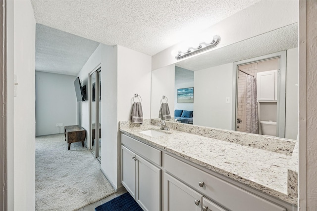 6050 Melody Ln Unit 107, Dallas, TX 75231 - ensuite bathroom featuring a textured ceiling, vanity, and a shower with curtain