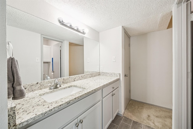 6050 Melody Ln Unit 107, Dallas, TX 75231 - bathroom with vanity, a textured ceiling, and wood finished floors