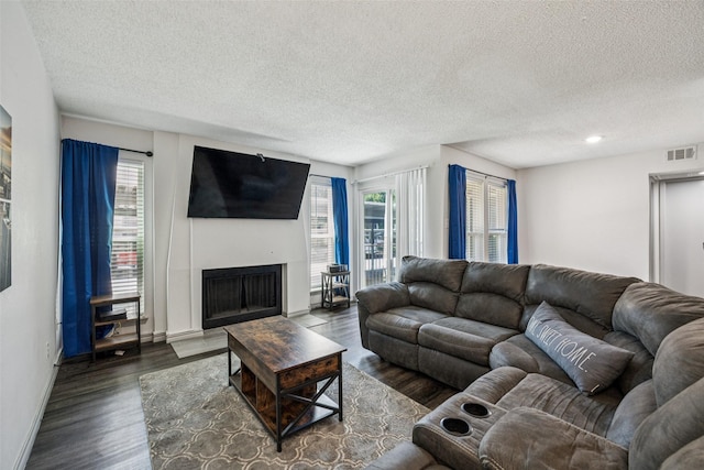6050 Melody Ln Unit 107, Dallas, TX 75231 - living room featuring a fireplace with flush hearth, healthy amount of natural light, a textured ceiling, and dark wood finished floors