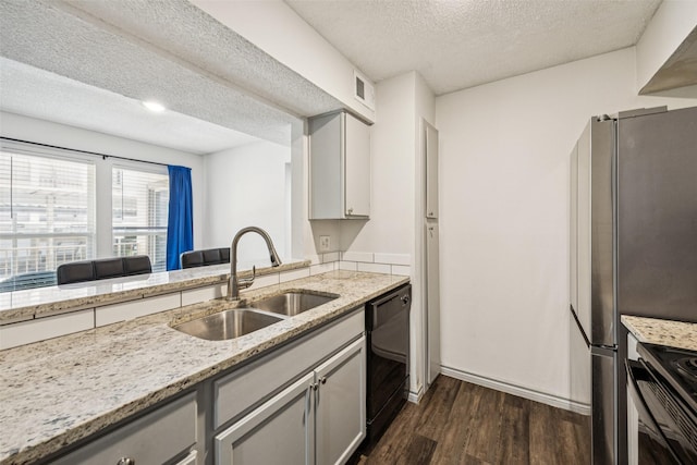6050 Melody Ln Unit 107, Dallas, TX 75231 - kitchen with black appliances, dark wood-style flooring, a textured ceiling, gray cabinets, and light stone countertops