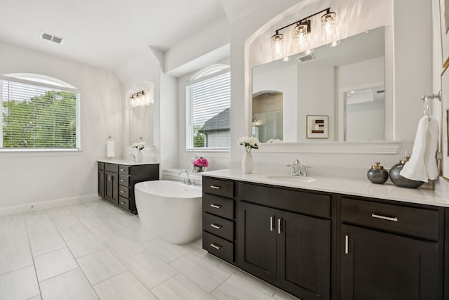 307 Misty Ln, Argyle, TX 76226 - bathroom featuring two vanities, healthy amount of natural light, a freestanding tub, and a tile shower