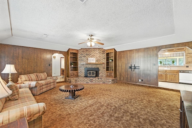 7220 Tucker Dr, Weatherford, TX 76085 - living room with wood walls, a textured ceiling, ceiling fan, built in shelves, and light colored carpet