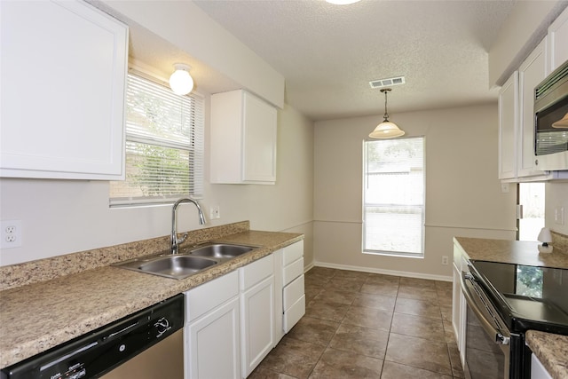 1209 Pin Oak Dr, Denton, TX 76209 - kitchen featuring appliances with stainless steel finishes, white cabinetry, a textured ceiling, decorative light fixtures, and dark tile patterned flooring