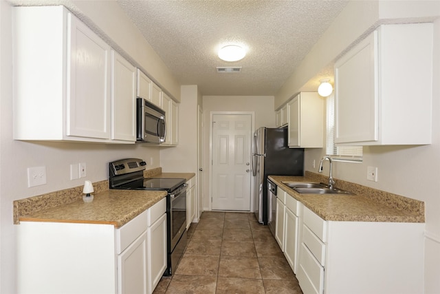 1209 Pin Oak Dr, Denton, TX 76209 - kitchen with appliances with stainless steel finishes, a textured ceiling, white cabinetry, and light countertops