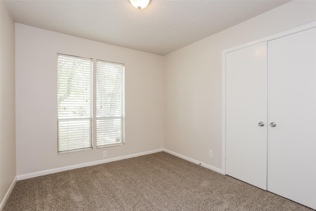 1209 Pin Oak Dr, Denton, TX 76209 - unfurnished bedroom featuring carpet, multiple windows, a closet, and a textured ceiling