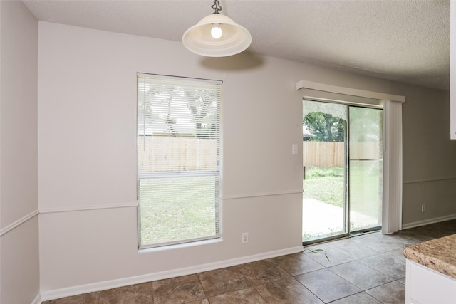 1209 Pin Oak Dr, Denton, TX 76209 - unfurnished dining area with a textured ceiling and baseboards