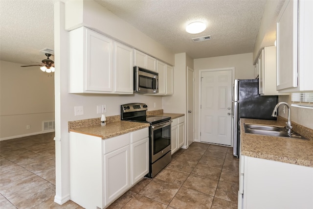 1209 Pin Oak Dr, Denton, TX 76209 - kitchen with stainless steel appliances, a textured ceiling, white cabinetry, ceiling fan, and tile patterned flooring