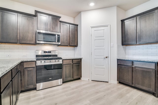 276 Jefferson Ln, Fate, TX 75189 - kitchen with appliances with stainless steel finishes, light wood-type flooring, dark brown cabinets, light stone countertops, and tasteful backsplash