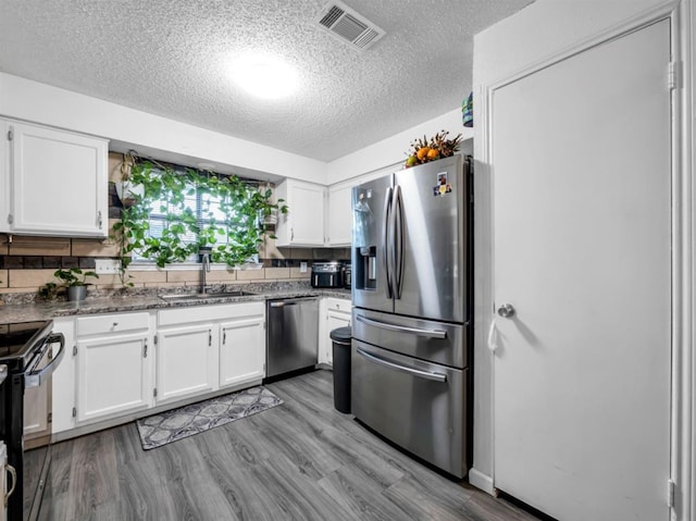 1013 Huntersglen Dr, Mesquite, TX 75150 - kitchen with stainless steel appliances, a textured ceiling, white cabinets, and tasteful backsplash