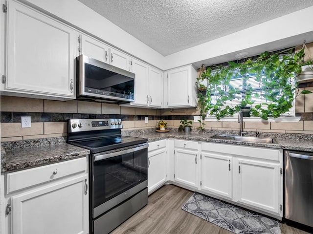 1013 Huntersglen Dr, Mesquite, TX 75150 - kitchen featuring stainless steel appliances, a textured ceiling, white cabinets, light wood finished floors, and tasteful backsplash
