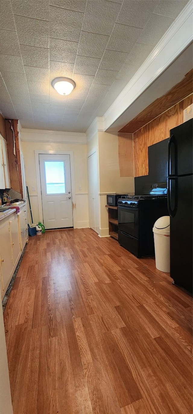 108 S Bonham St, Mexia, TX 76667 - kitchen with freestanding refrigerator, ornamental molding, light wood-style floors, and white cabinets