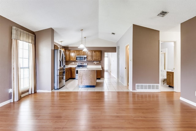 1524 Regent St, Mesquite, TX 75149 - kitchen with stainless steel appliances, light countertops, light wood-type flooring, brown cabinetry, and lofted ceiling