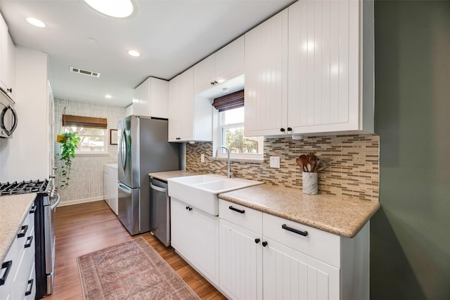 714 Silverstone Dr, Richardson, TX 75080 - kitchen with stainless steel appliances, plenty of natural light, light wood finished floors, white cabinetry, and recessed lighting