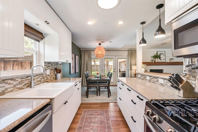 714 Silverstone Dr, Richardson, TX 75080 - kitchen featuring appliances with stainless steel finishes, decorative backsplash, white cabinetry, pendant lighting, and french doors