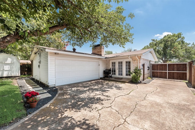 714 Silverstone Dr, Richardson, TX 75080 - back of property featuring french doors, a chimney, concrete driveway, brick siding, and an attached garage