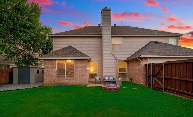 2904 Champlin Ct, Richardson, TX 75082 - back of property at dusk featuring brick siding, a storage unit, an outdoor fire pit, a fenced backyard, and a chimney