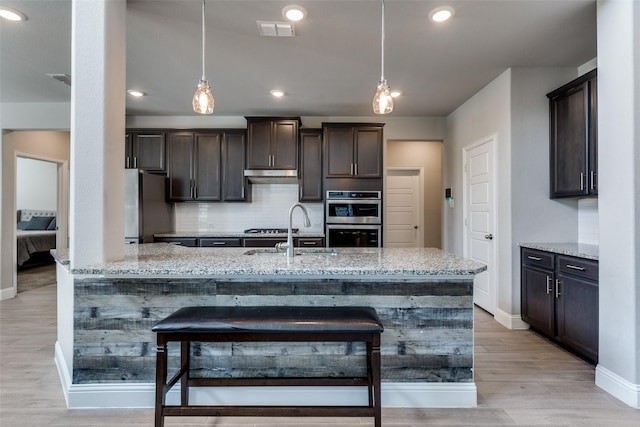 11825 Wulstone Rd, Fort Worth, TX 76052 - kitchen featuring stainless steel appliances, light stone countertops, dark brown cabinetry, decorative backsplash, and light wood-style floors