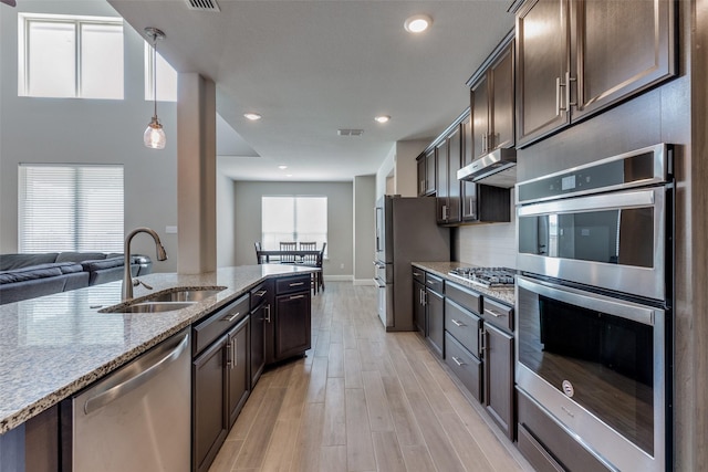 11825 Wulstone Rd, Fort Worth, TX 76052 - kitchen featuring stainless steel appliances, dark brown cabinets, light wood-style floors, light stone countertops, and under cabinet range hood
