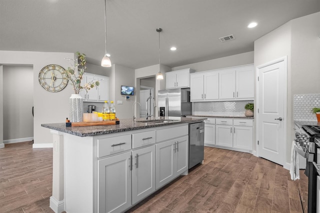 171 Tanager Dr, Rhome, TX 76078 - kitchen with stainless steel appliances, backsplash, a center island with sink, wood finished floors, and white cabinets