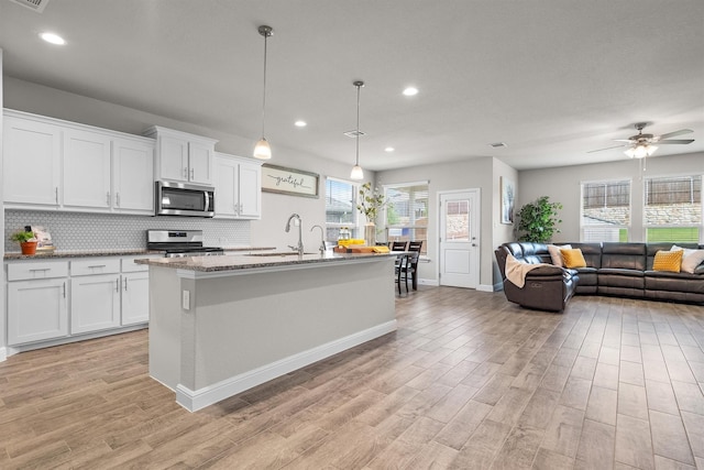 171 Tanager Dr, Rhome, TX 76078 - kitchen with appliances with stainless steel finishes, light wood finished floors, open floor plan, decorative backsplash, and white cabinets