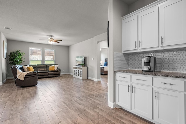 171 Tanager Dr, Rhome, TX 76078 - kitchen with backsplash, ceiling fan, dark stone countertops, light wood-style flooring, and white cabinetry