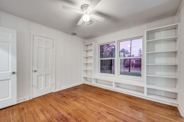 917 W Washington St, Sherman, TX 75092 - empty room featuring wood finished floors, a decorative wall, a ceiling fan, and built in shelves