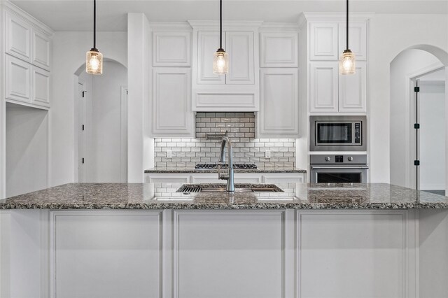 2604 Silverado Trl, Sherman, TX 75092 - kitchen with appliances with stainless steel finishes, arched walkways, white cabinetry, and decorative backsplash