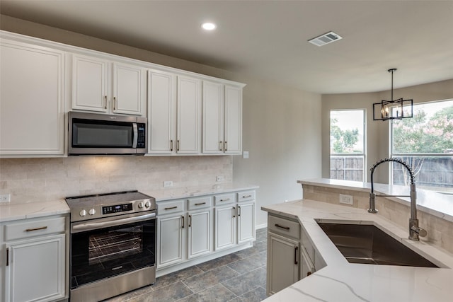 1432 Stillforest Dr, Allen, TX 75002 - kitchen with appliances with stainless steel finishes, a chandelier, decorative backsplash, light stone countertops, and white cabinetry