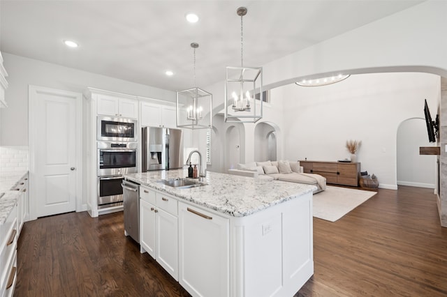 2751 Langley Way, Prosper, TX 75078 - kitchen with stainless steel appliances, arched walkways, white cabinets, dark wood-type flooring, and open floor plan