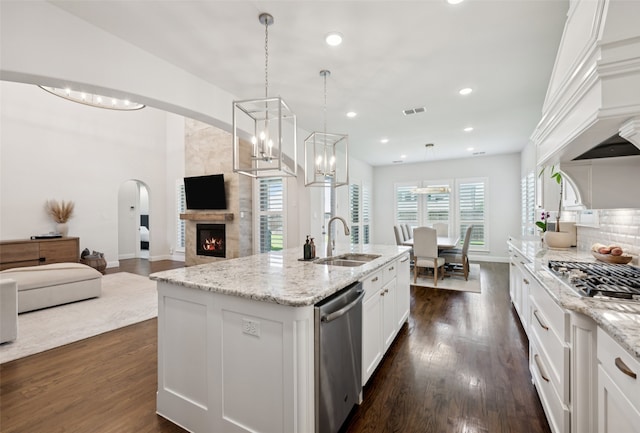 2751 Langley Way, Prosper, TX 75078 - kitchen featuring stainless steel appliances, arched walkways, white cabinets, a large fireplace, and dark wood-type flooring