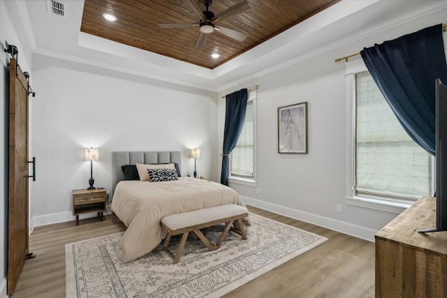 12457 Maplewood Dr, Lindale, TX 75771 - bedroom featuring a barn door, wood ceiling, a tray ceiling, multiple windows, and light wood finished floors