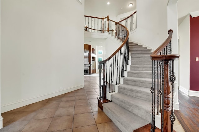 1910 Saint Johns Ave, Allen, TX 75002 - staircase featuring a high ceiling, a fireplace, and tile patterned floors