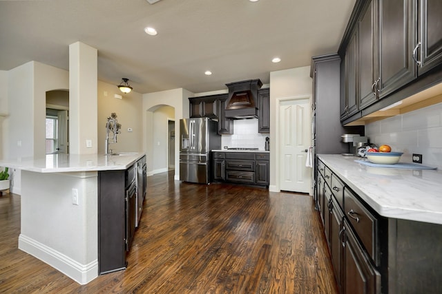 7219 Brisa Rd, Grand Prairie, TX 75054 - kitchen with arched walkways, appliances with stainless steel finishes, custom exhaust hood, backsplash, and dark wood-style flooring