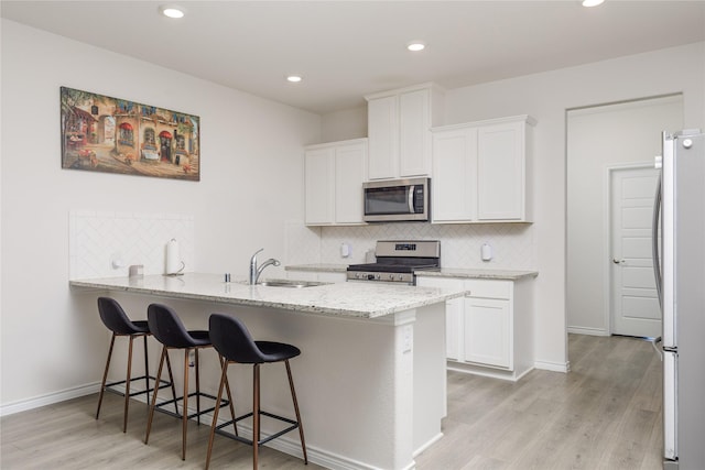 2265 Obsidian Dr, Little Elm, TX 76227 - kitchen with appliances with stainless steel finishes, tasteful backsplash, a peninsula, white cabinetry, and recessed lighting