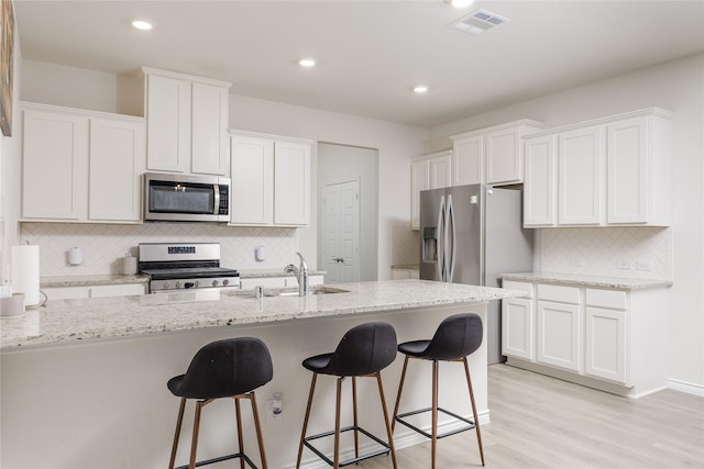 2265 Obsidian Dr, Little Elm, TX 76227 - kitchen featuring stainless steel appliances, decorative backsplash, white cabinetry, a kitchen breakfast bar, and recessed lighting