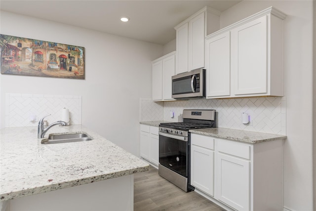 2265 Obsidian Dr, Little Elm, TX 76227 - kitchen featuring appliances with stainless steel finishes, tasteful backsplash, white cabinetry, light stone counters, and light wood-style floors