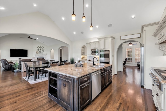 1400 Lakeside Dr, Prosper, TX 75078 - kitchen featuring ceiling fan, stainless steel appliances, arched walkways, lofted ceiling, and light stone countertops