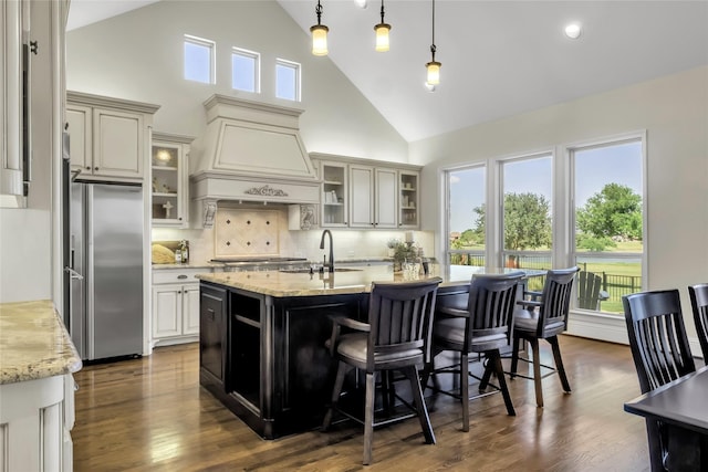1400 Lakeside Dr, Prosper, TX 75078 - kitchen with stainless steel refrigerator, high vaulted ceiling, custom exhaust hood, a kitchen island with sink, and decorative backsplash