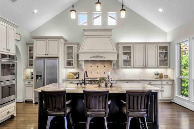 1400 Lakeside Dr, Prosper, TX 75078 - kitchen with appliances with stainless steel finishes, light stone countertops, custom exhaust hood, a kitchen breakfast bar, and high vaulted ceiling