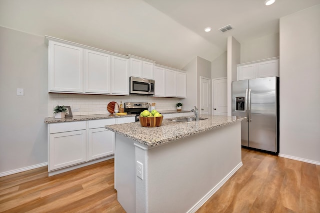 5361 Brentlawn Dr, Fort Worth, TX 76179 - kitchen with stainless steel appliances, light wood-style flooring, decorative backsplash, white cabinets, and lofted ceiling