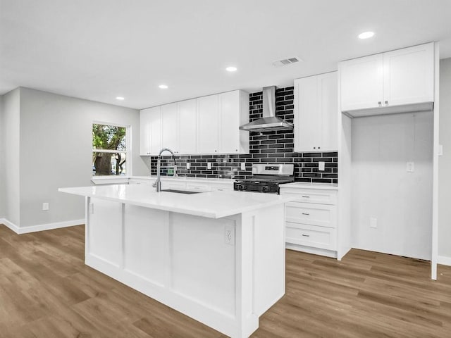 3505 Morningstar Ln, Farmers Branch, TX 75234 - kitchen with wall chimney exhaust hood, gas range oven, wood finished floors, backsplash, and an island with sink