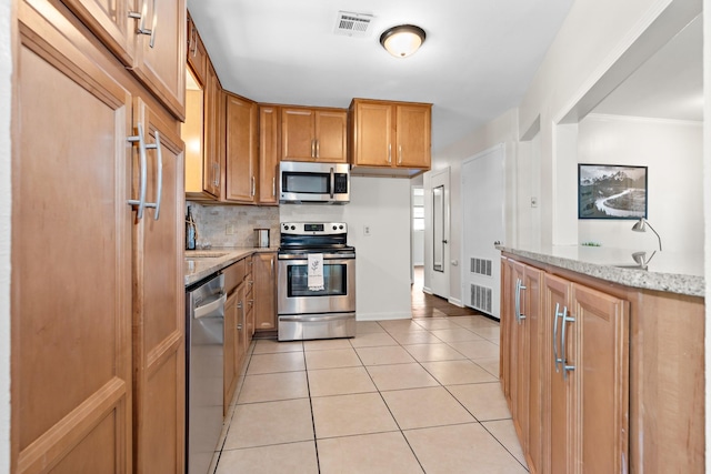 301 Sunset Blvd, Hewitt, TX 76643 - kitchen with appliances with stainless steel finishes, light stone countertops, light tile patterned flooring, decorative backsplash, and brown cabinetry